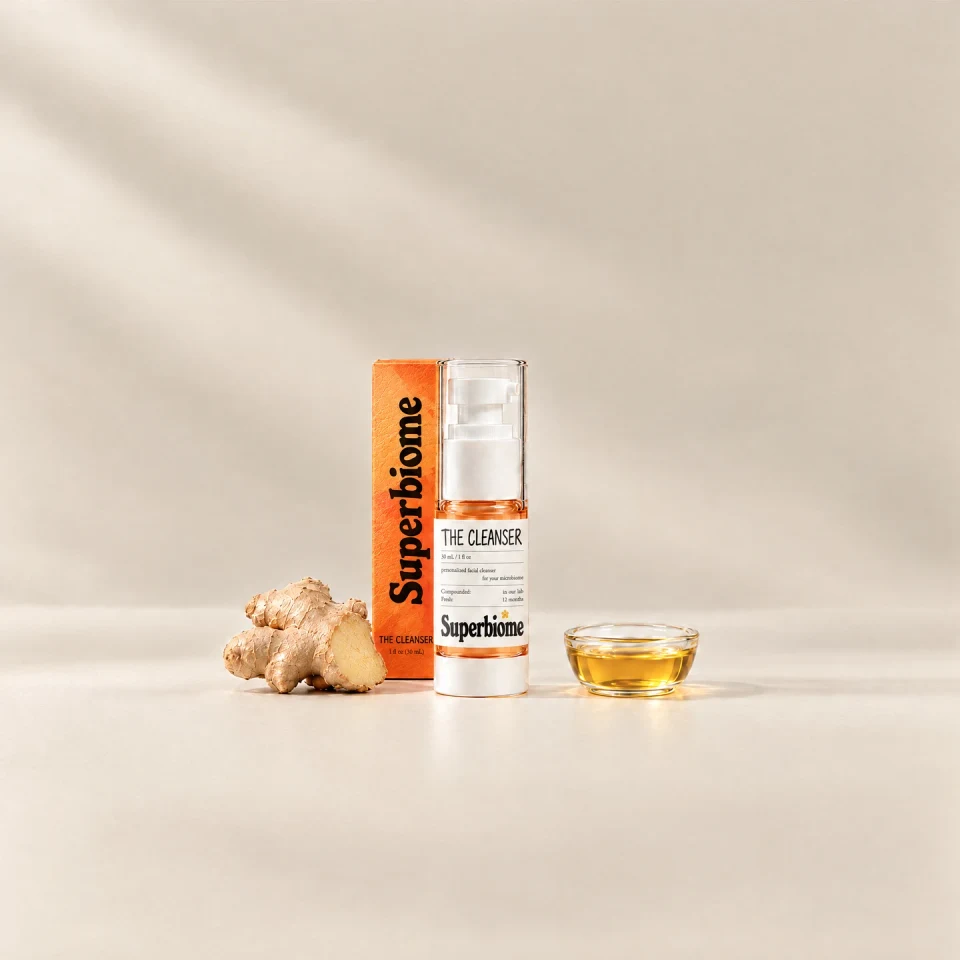 A Skin Nutrients Cleanser bottle with its orange box, beside fresh ginger root and a small dish of golden oil
