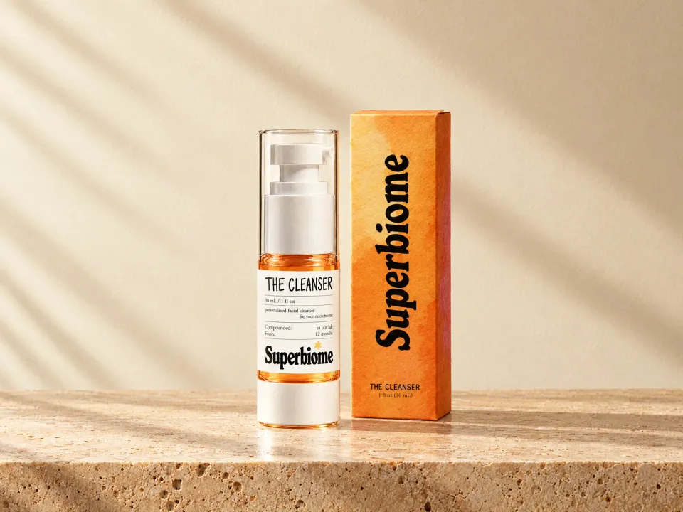 A Skin Nutrients Cleanser bottle with its orange box on travertine